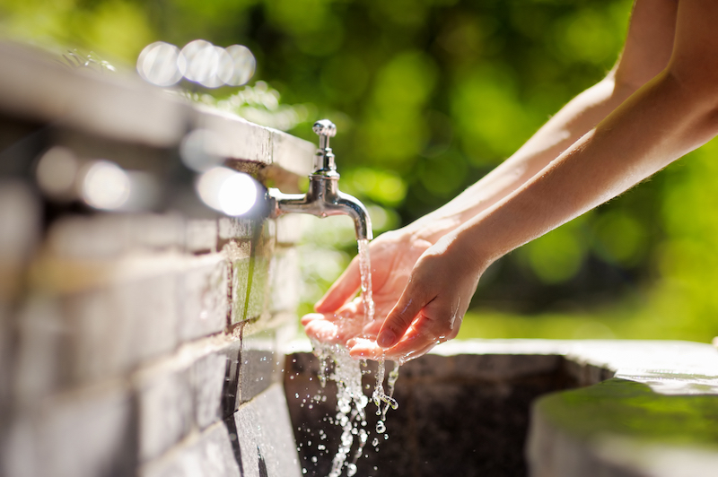 Closeup photo of woman washing hands in a city fountain 