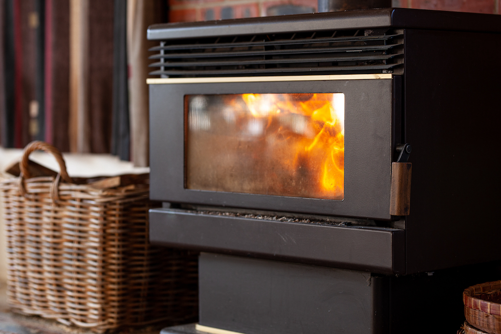 black metal stove fireplace with a burning flame behind a glass door in the interior